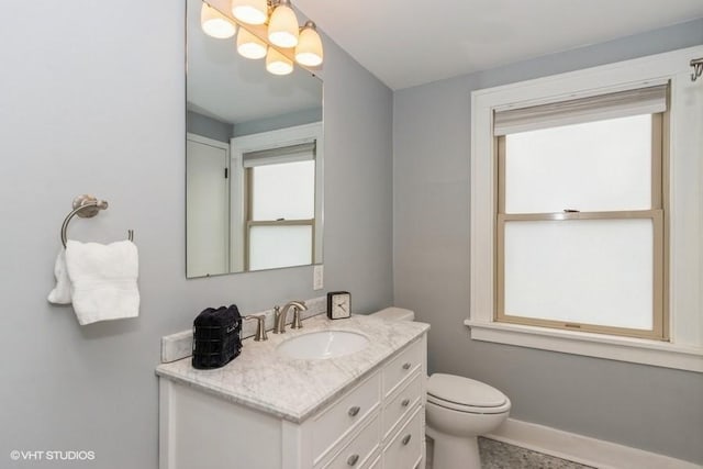 bathroom with vanity, baseboards, a chandelier, and toilet