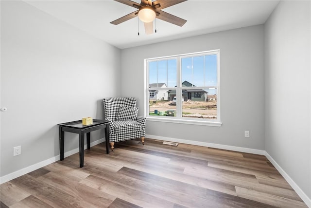 living area with a ceiling fan, wood finished floors, and baseboards