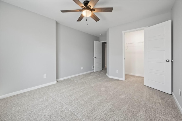 unfurnished bedroom featuring light carpet, baseboards, a walk in closet, and a closet