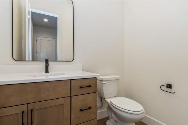938 Heron Pl, Iowa City, IA 52245 - half bathroom featuring baseboards, vanity, toilet, and wood finished floors