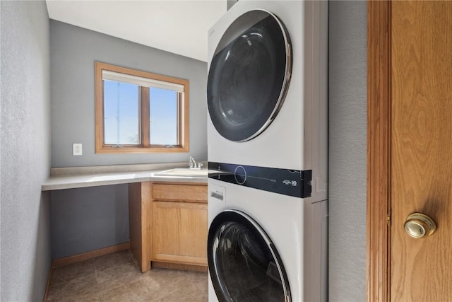 5141 25th Ave, Brandon, IA 52210 - washroom with stacked washer and dryer, cabinet space, a sink, baseboards, and light tile patterned flooring