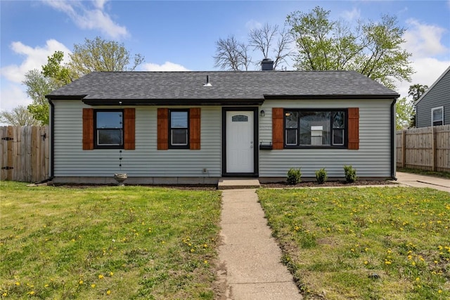 view of front facade with roof with shingles, fence, and a front yard