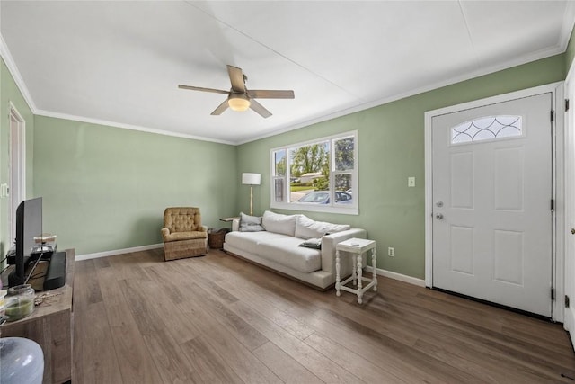 interior space featuring baseboards, ornamental molding, a ceiling fan, and wood finished floors