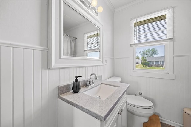 bathroom featuring crown molding, a wainscoted wall, vanity, and toilet