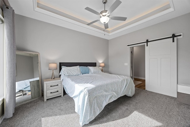 carpeted bedroom featuring crown molding, a barn door, a raised ceiling, and ceiling fan