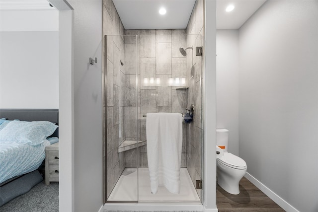 ensuite bathroom with wood finished floors, toilet, ensuite bathroom, baseboards, and a stall shower