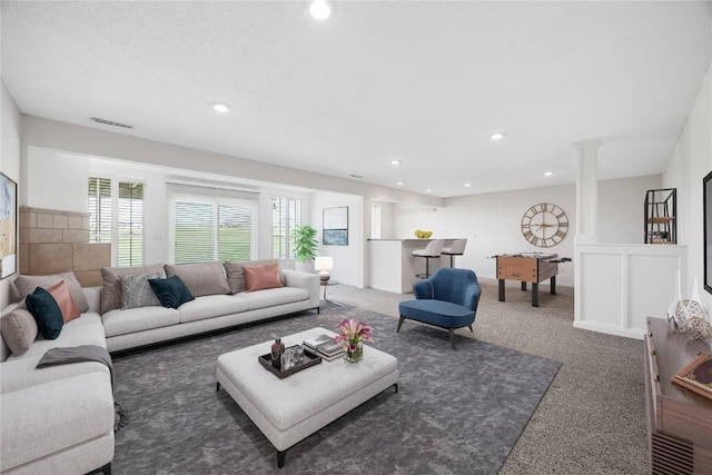 carpeted living area featuring recessed lighting, decorative columns, and visible vents
