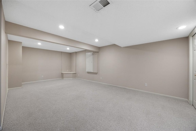 finished below grade area with visible vents, recessed lighting, baseboards, and light carpet