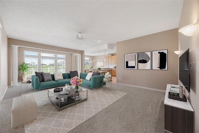 living room featuring a ceiling fan, light colored carpet, and a healthy amount of sunlight