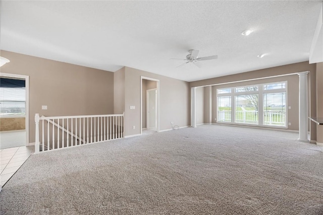 carpeted spare room featuring baseboards, a ceiling fan, a textured ceiling, and a healthy amount of sunlight