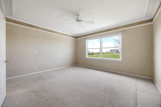carpeted spare room featuring crown molding, a ceiling fan, and baseboards
