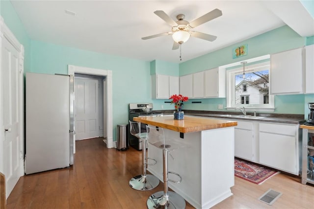 kitchen with wooden counters, visible vents, appliances with stainless steel finishes, a sink, and white cabinets