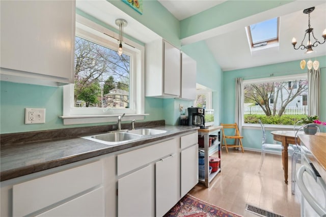kitchen with white cabinets, a wealth of natural light, and a sink