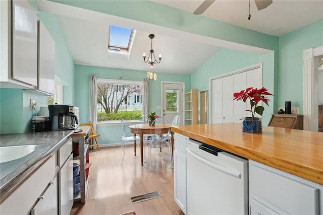kitchen featuring white cabinets, white dishwasher, light wood-type flooring, visible vents, and lofted ceiling with skylight