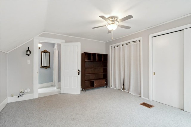 unfurnished bedroom featuring a ceiling fan, light colored carpet, lofted ceiling, and visible vents