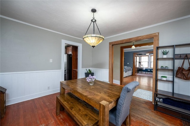 dining space with crown molding, wainscoting, and wood finished floors