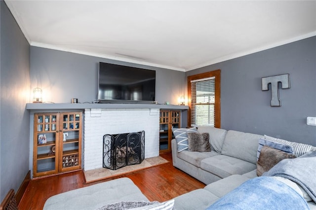 living area featuring baseboards, ornamental molding, wood finished floors, and a fireplace