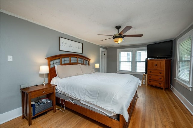 bedroom featuring crown molding, a ceiling fan, baseboards, and wood finished floors