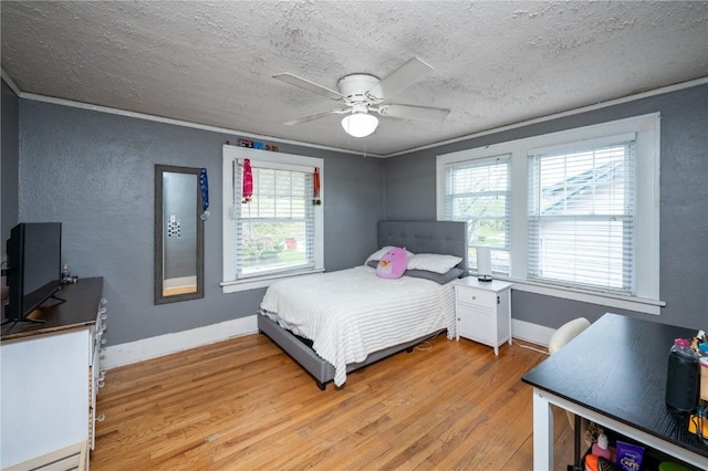 bedroom with ceiling fan, a textured wall, a textured ceiling, light wood-style flooring, and baseboards