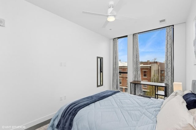 bedroom featuring baseboards, ceiling fan, visible vents, and a wall of windows