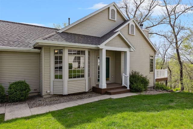 view of front of home with a front lawn, roof with shingles, and a chimney