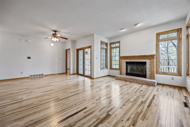unfurnished living room with light wood-style floors, plenty of natural light, a textured ceiling, and visible vents