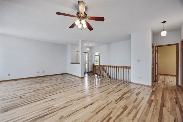 unfurnished living room with baseboards, a ceiling fan, and light wood-style flooring