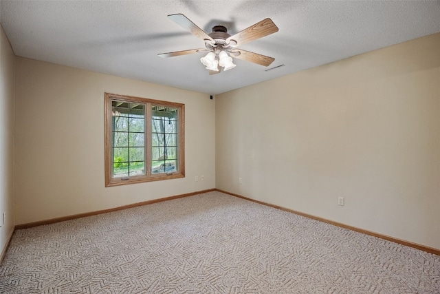 spare room featuring carpet floors, a ceiling fan, baseboards, and visible vents