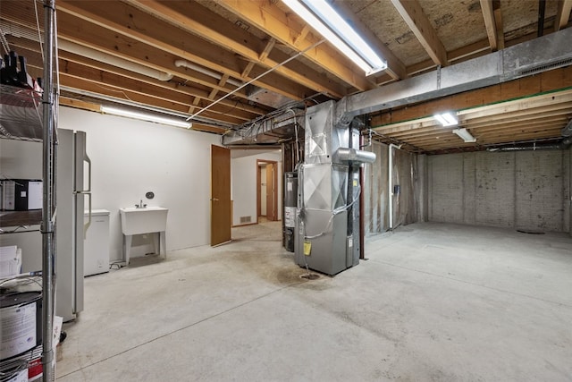 unfinished below grade area featuring heating unit, gas water heater, and a sink