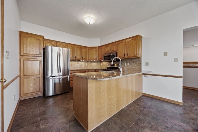 kitchen featuring a peninsula, a textured ceiling, appliances with stainless steel finishes, and decorative backsplash
