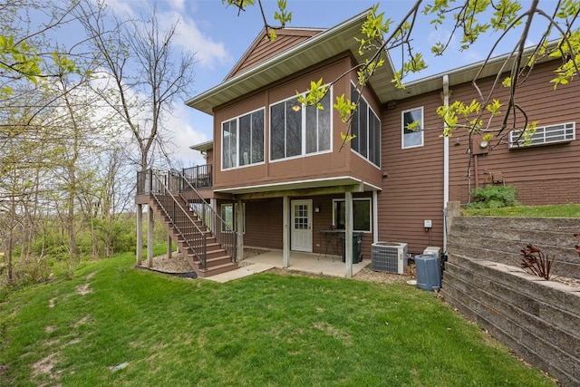 back of house with stairs, a sunroom, cooling unit, a lawn, and a patio