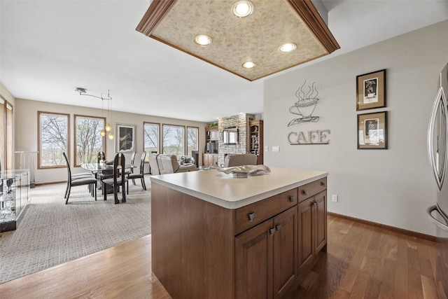 kitchen featuring baseboards, light countertops, light wood finished floors, and pendant lighting
