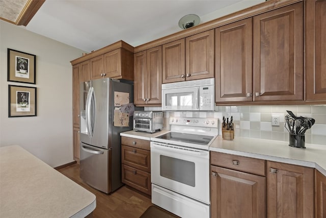kitchen with white appliances, decorative backsplash, brown cabinetry, and light countertops