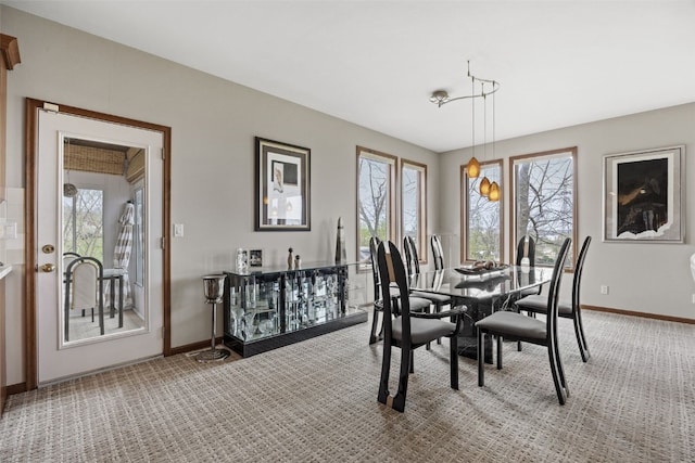 dining area with baseboards, a wealth of natural light, and light colored carpet