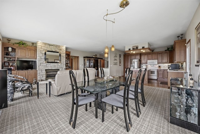 dining space with light carpet and a stone fireplace