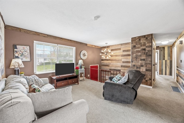living area featuring visible vents, wood walls, carpet, and an inviting chandelier