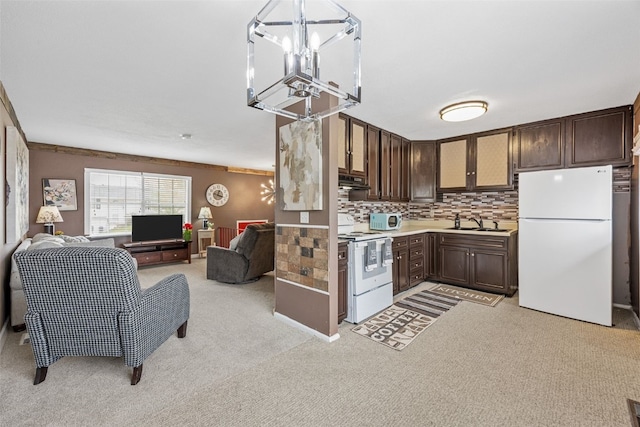 kitchen with dark brown cabinets, white appliances, open floor plan, light countertops, and a sink