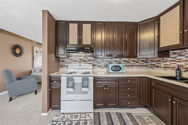 kitchen with a sink, light countertops, under cabinet range hood, and white appliances