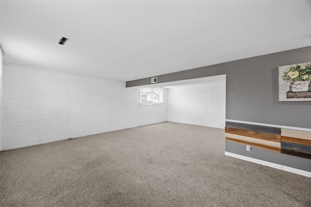 carpeted spare room featuring brick wall, visible vents, and baseboards