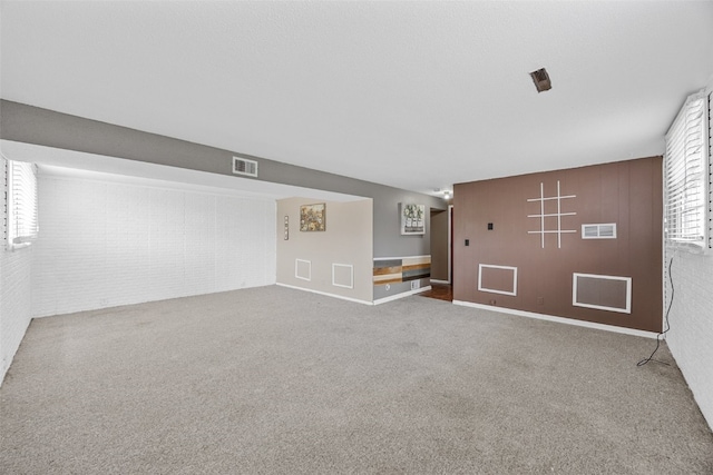 interior space featuring carpet flooring, brick wall, visible vents, and baseboards