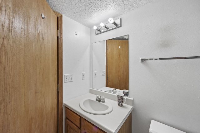 half bathroom with toilet, a textured ceiling, and vanity