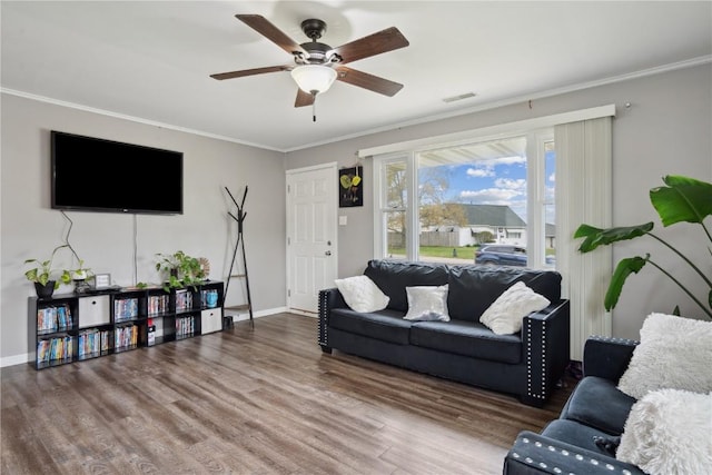 living room featuring visible vents, crown molding, wood finished floors, baseboards, and ceiling fan