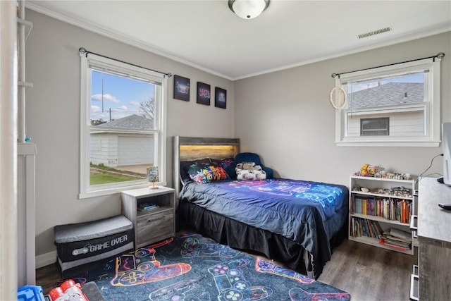 bedroom with ornamental molding, wood finished floors, and visible vents