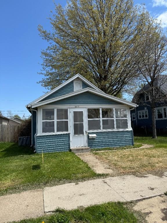 bungalow-style house featuring a sunroom and a front lawn