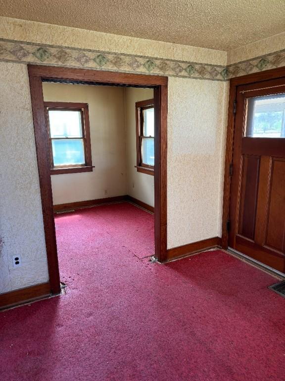 spare room featuring carpet floors, baseboards, a textured ceiling, and visible vents