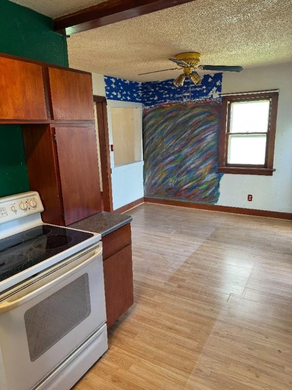 kitchen featuring baseboards, white electric stove, and light wood finished floors