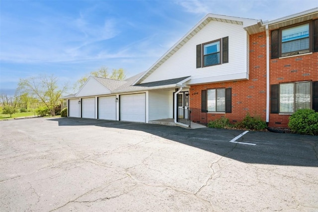 view of front facade with an attached garage, aphalt driveway, and brick siding