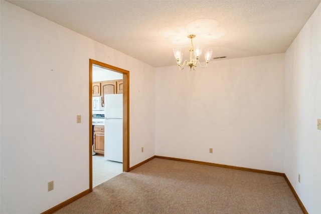 spare room featuring an inviting chandelier, baseboards, visible vents, and light colored carpet