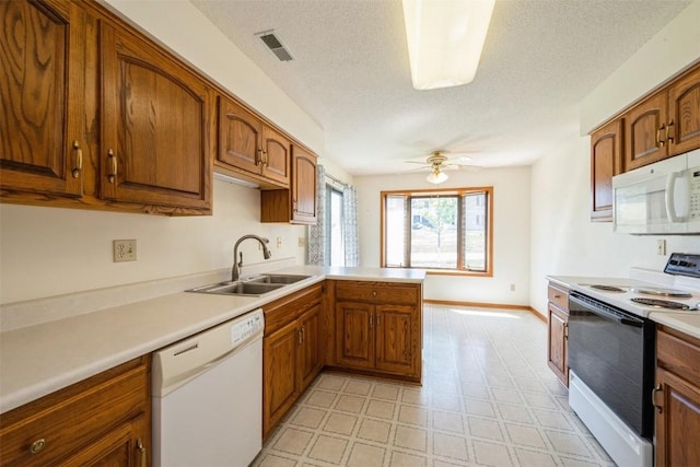 kitchen with a sink, brown cabinets, white appliances, and light countertops