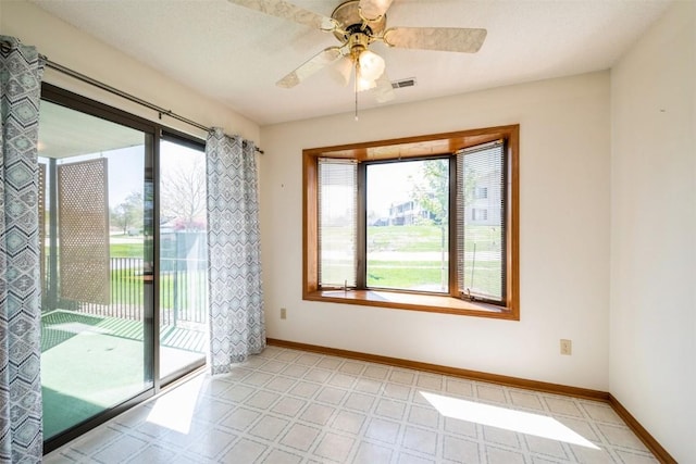 empty room featuring plenty of natural light, light floors, and baseboards